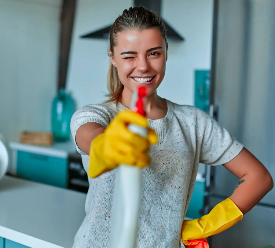 Smiling cleaner holding a spray bottle